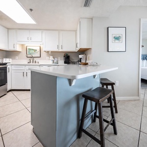 Kitchen features a breakfast bar with seating, white cabinetry, and a coffee corner with Keurig and coffee maker