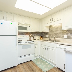 Kitchen featuring white cabinets, white appliances, and a cozy coffee maker for your morning brew