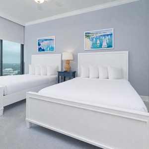 Rest in this serene room with two queens, decorative artwork, and coastal views