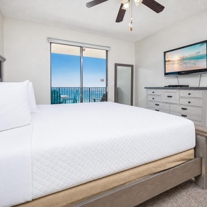 The king master suite offers a restful retreat with a balcony that overlooks shimmering blue waters beyond the horizon