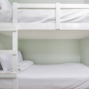 This cozy nook features a white bunk bed with fresh linens, perfect for kids or extra guests