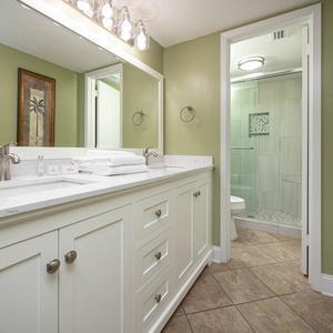Bright and inviting master bathroom featuring a modern vanity, walk-in shower, and elegant palm tree artwork on the walls