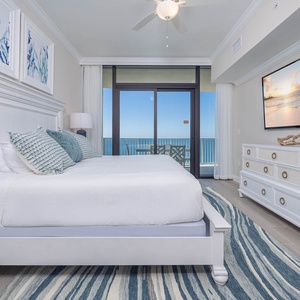 Unwind in the master suite featuring a plush king bed, large TV, and beachfront balcony access