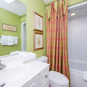Immerse yourself in relaxation in this guest bath with plush towels and vibrant decor enhancing your refreshing routine