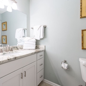 Stylish guest bathroom with a marbles countertop, fresh towels, and charming artwork enhancing the space