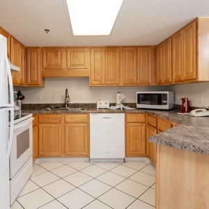 Fully-equipped kitchen featuring wooden cabinetry, white appliances, and ample counter space for meal prep