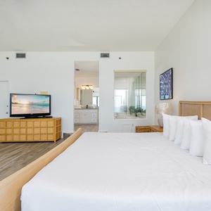 Relaxing master bedroom featuring a king bed, modern TV, and an inviting view through the adjoining bathroom