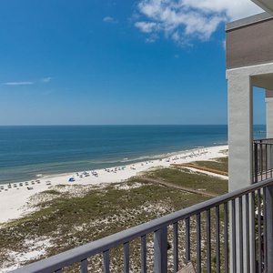 View showcasing the white sand beach and turquoise gulf waters, with beach chairs dotting the shoreline