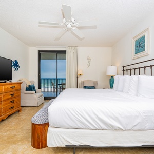 Relax in the spacious master bedroom with a comfortable king bed, a cozy seating area, and beachfront balcony access