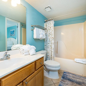 Bright bathroom featuring a tub/shower combo, decorative shower curtain with beach motifs, and a cozy feel