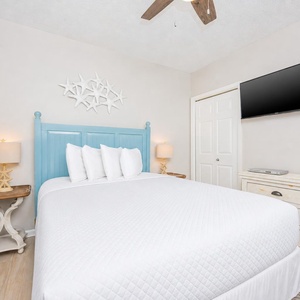 Relax in this inviting guest bedroom featuring a queen bed, coastal decor, and a TV for your entertainment