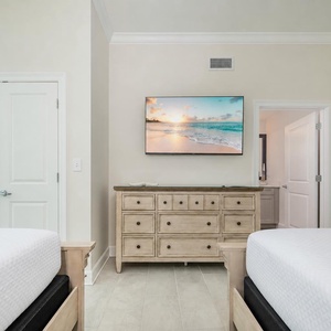 Relax in this inviting bedroom featuring two queen beds, a large TV, and a serene vibe for restful nights