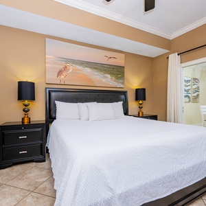 The master bedroom features a comfortable king bed with a serene beach-themed artwork, creating a relaxing atmosphere