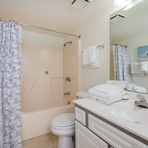 Guest bathroom featuring a tub/shower combo, a large mirror, and neatly arranged fluffy towels for a refreshing stay