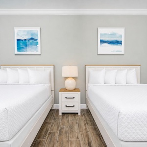 Rest comfortably in this guest room featuring two queens, soft pillows, and serene artwork