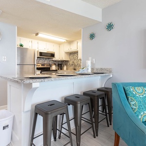 This modern kitchen features sleek stainless appliances and a cozy bar area with seating, perfect for casual dining