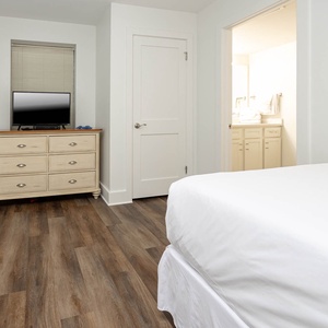 Comfortable guest bedroom featuring two double beds, a TV, and easy access to a bathroom for your convenience