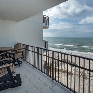 Relax on the balcony with comfortable seating, enjoying the view of the beach and gentle waves below