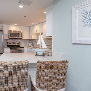 Bright, modern kitchen features sleek stainless appliances, a marble breakfast bar, and coastal decor for a welcoming vibe