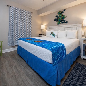 This guest bedroom features a vibrant blue bedspread, decorative sea-themed art, and a comfortable atmosphere for relaxation