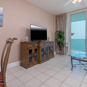 This inviting living area features a large TV, stylish cabinetry, and a stunning beachfront view from the sliding glass doors