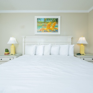 Sleep soundly in this guest room featuring a king bed, coastal artwork, and cheerful lamps for a relaxing retreat