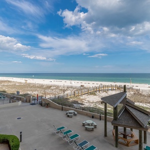 Serene beachfront with white sand, lounge chairs, and a shaded area for relaxation