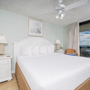 Master bedroom features a king bed, stylish bedside lamps, and a balcony offering a view of the gulf