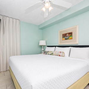 Rest comfortably in this serene bedroom featuring a king bed, a TV, and calming teal walls for a restful retreat