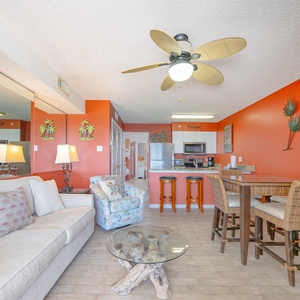 This vibrant living area features a cozy sofa, a large TV, and a stunning beachfront view from the sliding glass doors