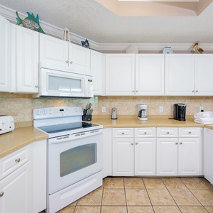 Prepare meals in this kitchen with sleek cabinetry, white appliances, and spacious countertops