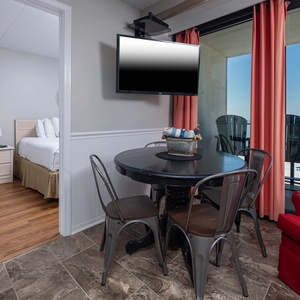 This inviting dining area features a round table, cozy seating, and stunning beachfront views from the balcony