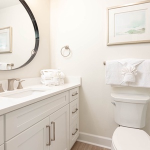 This bathroom features a vanity with a large mirror, elegant fixtures, and neatly arranged towels for a refreshing experience