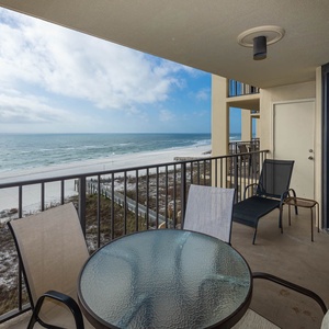 Balcony patio furniture offers a serene view of the tranquil beach and gentle waves
