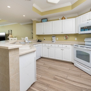 Prepare meals in this kitchen with sleek cabinetry, white appliances, and spacious countertops