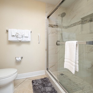 This bathroom features a sleek glass shower, plush towels, and elegant tile work for a refreshing experience