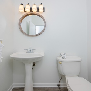 Additional half bath featuring a stylish round mirror, elegant lighting, and fresh white towels for a refreshing retreat