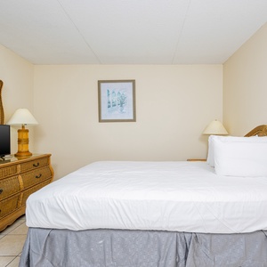 This confortable bedroom features a cozy bed, stylish wicker furniture, and a TV for relaxing evenings