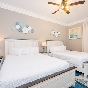 Cheerful guest bedroom featuring two queen beds, coastal decor, and stylish accents