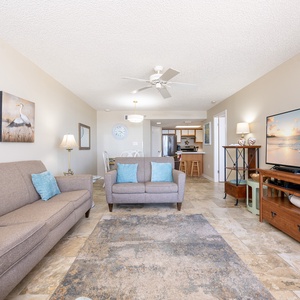 Living space features two sofas, a large TV, and a dining area, creating a welcoming space for relaxation