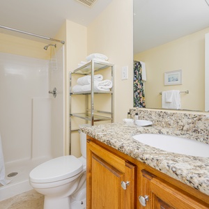 The master bathroom features a vibrant shower curtain, granite countertops, and neatly arranged towels for a refreshing stay