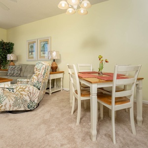 The inviting living area features a floral-patterned chair, a cozy sofa with queen sleeper, and dining table