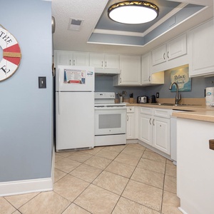 Inviting kitchen featuring white cabinetry, white appliances, and beach decor for a cheerful experience