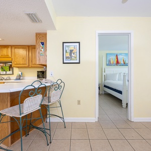 Kitchen area featuring wooden cabinetry, a breakfast bar with seating, and a view into a cozy bedroom with nautical decor