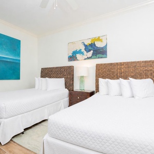 This guest bedroom features two comfortable queen beds, vibrant artwork, and a stylish nightstand, perfect for a restful stay