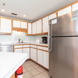 The light cabinetry complements the spacious layout, featuring a breakfast bar and stainless appliances