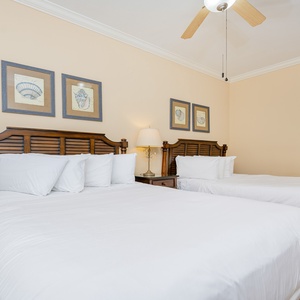 Inviting guest bedroom featuring two comfortable queen beds and charming coastal artwork for a relaxing stay