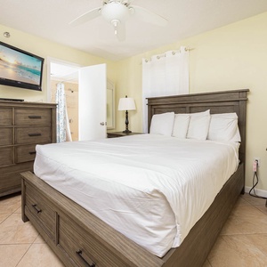 Cozy guest bedroom featuring a queen bed, stylish wooden furniture, and a wall-mounted TV for relaxing evenings