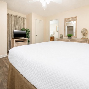 Cozy guest bedroom featuring a plush king bed, TV, and tasteful decor, with a bathroom just steps away