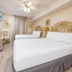 Brightly decorated guest bedroom featuring two double beds, TV, and charming artwork, creating a welcoming retreat